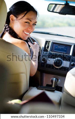 Smiling female driver looking over her shoulder into the rear seat of the car