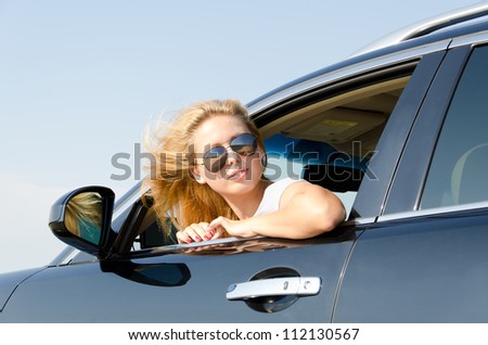 Attractive blonde woman in sunglasses leaning out and looking back from the car window