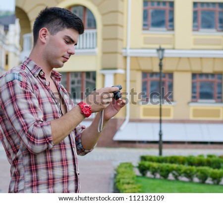 Man checking the viewfinder at the back of a camera to check the photograph that he has just taken