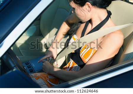 Woman driver leaning down to tighten her safety belt before driving away