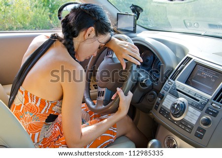 Tired woman driver taking a break leaning her head on the steering wheel for a five minute nap to refresh herself