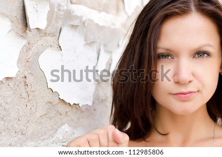 Headshot of a beautiful woman posing againsta grunge wall with peeling paint and exposed concrete