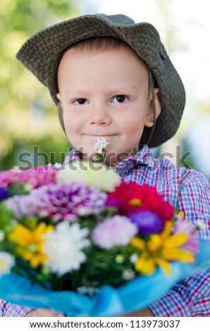Little boy in a hat with a large bunch of colourful flowers for Mum on Mothers Day