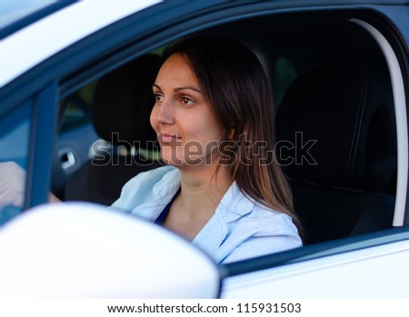 View through the open side window of an attractive female driver in a car