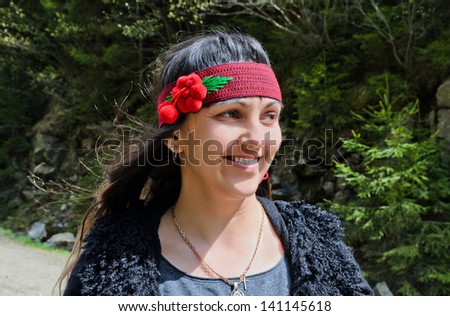 Happy pretty young hippie woman smiling outdoors, wearing a red headband decorated with flowers
