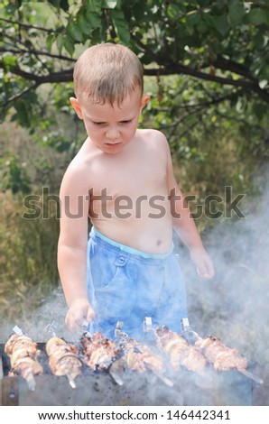 Young Shirtless Boy Cooking At A Barbecue Standing Over The Smoking ...