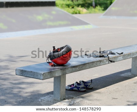 Safety gear for roller skating left abandoned by a child on a park bench with a safety helmet, knee pads and pair of sneakers