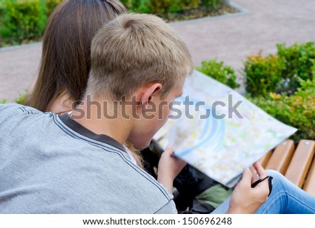 Over the shoulder view of a young couple planning a journey looking at a map
