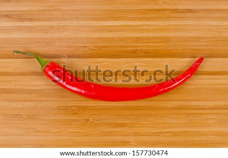 Vegetable smile formed from a whole fresh red hot chilli pepper for wood background