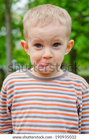 Cute young boy pulling a funny expression puckering up his lips with a look of amusement in his eyes