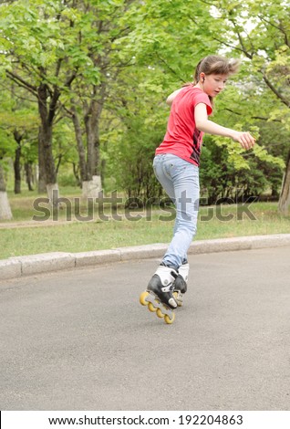 Young teenage girl skating on roller blades along a rural tree lined road turning her head to watch something on her right as she speeds along
