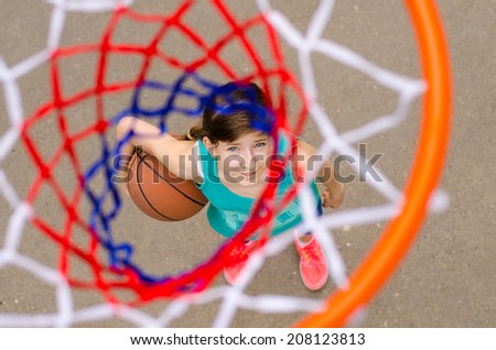 Young girl standing with basketball under hoop