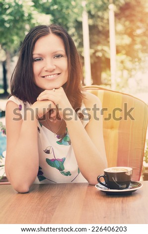Smiling lady sitting in a comfortable chair in her garden enjoying a cup of capuccino