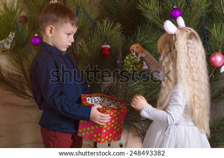 Close up White Kids, in Trendy Outfits, Amazed with Beautiful Christmas Ball from the Box.
