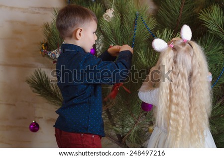 Close up Young Boy and Girl Busy Decorating a Huge Christmas Tree at Home.