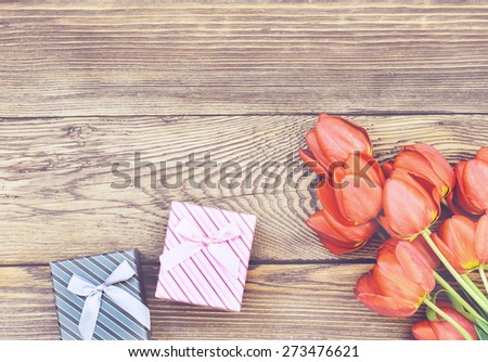 Bouquet of Fresh Orange Tulip Flowers on Top of Wooden Table with Two Gift Boxes, Captured in High Angle View.