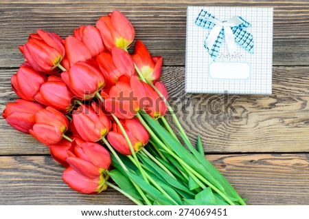 Bouquet of Fresh Orange Tulip Flowers on Top of Wooden Table with Gift Boxes, Captured in High Angle View.