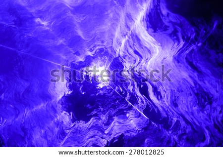 Blue spotlight shining through a haze of swirling smoke creating an interesting abstract pattern
