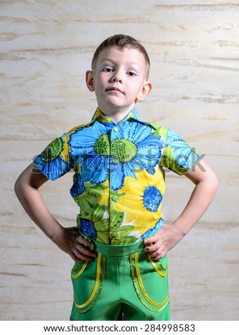 Young Boy Wearing Colorful Floral Print Collar Shirt Standing with Hands on Hips and Looking Serious in Studio with Patterned Background