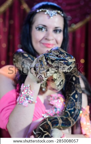 Portrait of Dark Haired Exotic Snake Charmer Female Dancer with Large Snake Around Neck Smiling at Camera