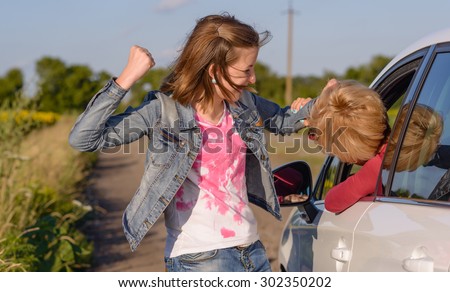 Two women having a fight with a young woman standing on the roadside punching the female driver in a car on the head, rural road