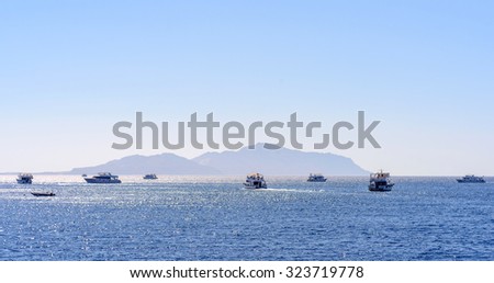Group of tour ships and dive boats moored off an offshore reef and sand bar in a calm blue tropical ocean on a hot summer day