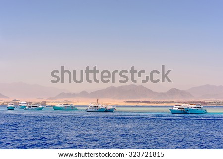 Group of tour ships and dive boats moored off an offshore reef and sand bar in a calm blue tropical ocean on a hot summer day