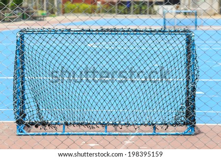 Goal net for small football metal blue concrete floor yard	fence surround and plant trees