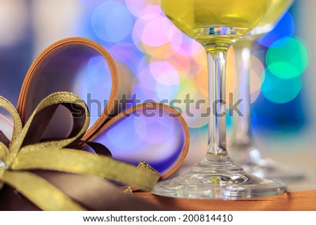 Pair glass of wine dinner sweet in love have bokeh gold ribbon and book make-shaped heart, colorful bokeh background.