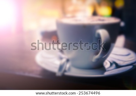 Blur a cup of Cappuccino with retro style coffee shop background memory under light classica tea in a glass of water background