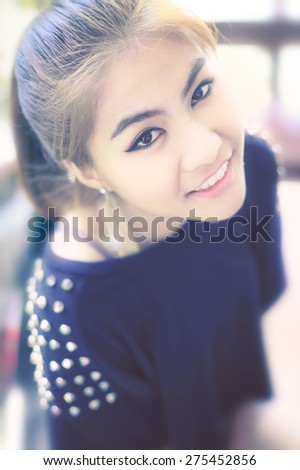 woman Asia Smiling Teeth and looking camera bird\'s-eye teenager gold-brown hair ,make up eye-liner and other ,wearing black T-shirt ,expression so friendly at coffee shop