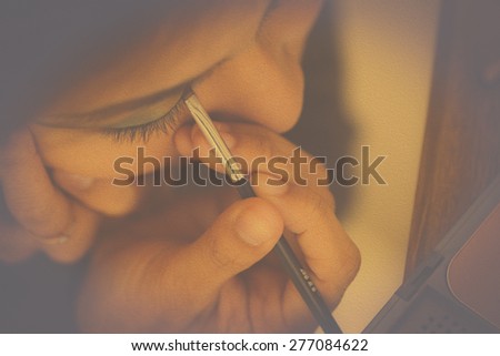 Oil paint style Close up macro lens depth of field show fingers Hands of woman with contact lens brown eyes Make up eye with black brush,look film camera behind the scenes style