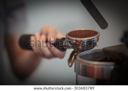 The hand of a young woman preparing cup of coffee, close up professional coffee machine
