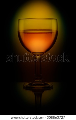 goblet of white wine on black background shadow effect yellow glow