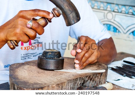 YOGYAKARTA, INDONESIA - SEPTEMBER 15: Man making traditional shadow puppet with leather and hammer in workshop in Yogyakarta, Indonesia on Sept 15, 2014