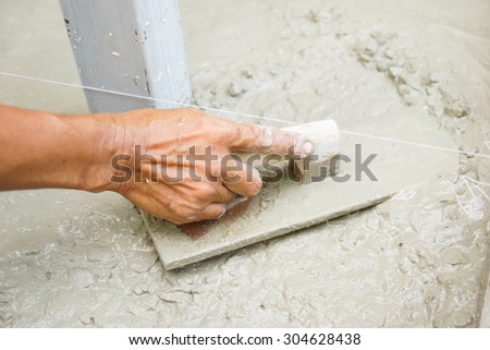 worker\'s hand using trowel to finish wet concrete floor