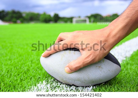 rugby ball in hand on green grass