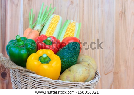 Fruits and vegetables in wicker basket on wood background