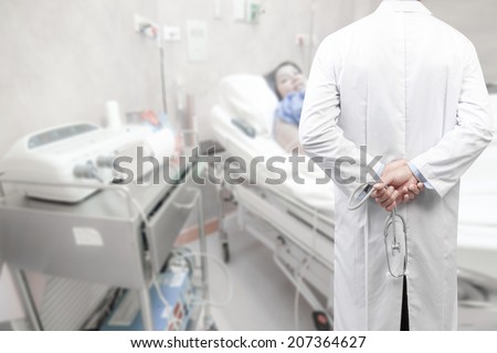 rear view image of doctors with stethoscope in a hospital pose arms crossed behind back looking at nurse pushing stretcher gurney bed in labour room of hospital corridor with female patient pregnant