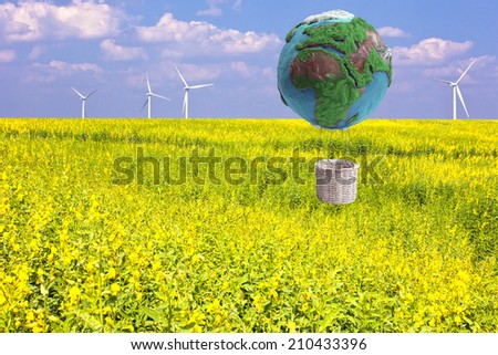 globe hot air balloon basket in a flower field and wind turbines in concept eco power