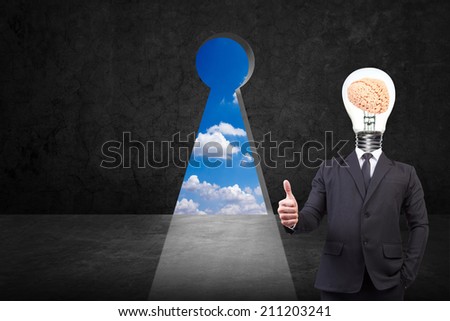 businessman thumb up and head brain inside a light bulb front of key hole on old grunge black wall against blue sky background