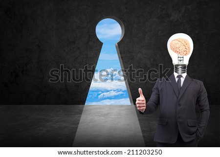 businessman thumb up and head brain inside a light bulb front of key hole on old grunge black wall against bright blue sky background