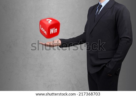 businessman presenting red dice and word win or lose against concrete wall