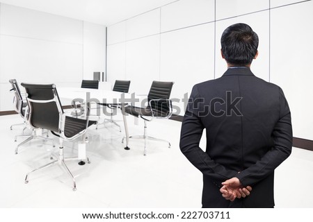 rear view of businessman smart intelligent wearing black suit posted stance looking to the future at conference room in modern office interior