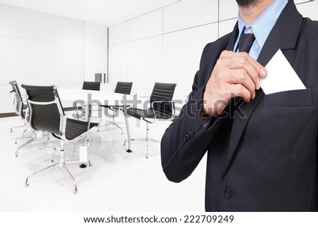 business man takes out business card from the pocket of business suit at conference room in modern office interior