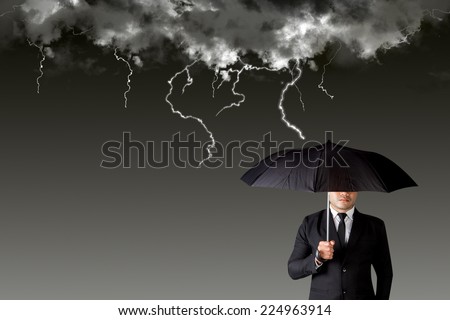 Businessman with an umbrella among rain storm and lightning concept of protection obstacle and trap on the way of a business