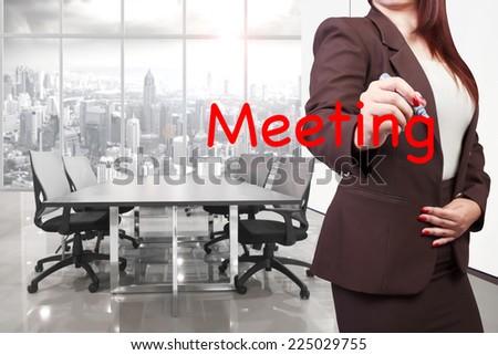 business woman with pen writing word meeting on virtual screen about a business concept at conference room in modern office interior on high building