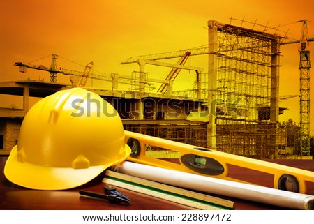 engineer working table plan and writing tool equipment against building construction crane with beautiful sunset