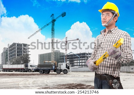 technician in protective safety equipment working in building construction site with tower crane and blue sky