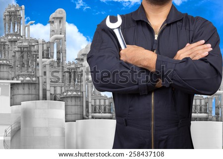 mechanic holding wrench for maintaining at petrochemical Industrial plant with blue sky